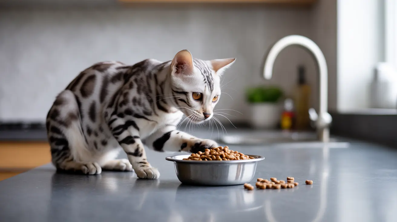 Silver and black spotted Bengal cat next to metal bowl filled with dry cat food on kitchen counter